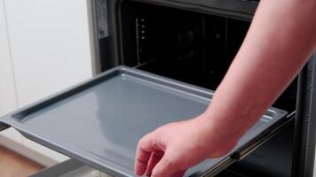 Close-up of hands placing dough in a baking dish into the oven. the cook bakes bread. video
