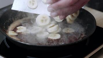 Add raw chopped bananas to the pans. Raw sliced bananas boiled in oil. Caramelization of bananas. video