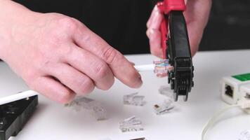 Engineer installs a new connector on a cable using a tool. Tool for crimping internet cable, cable and connectors on the desktop. video
