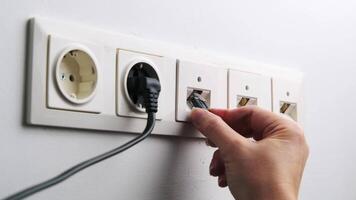 Close-up of a woman's hand connecting an Ethernet cable to a network socket in the wall, broadband network concept. video
