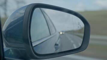 Side view mirror reflects road and distant headlights while car moves forward video