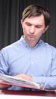 vertical Office worker reviewing documents in red folder at desk video