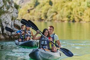 A group of friends enjoying having fun and kayaking while exploring the calm river, surrounding forest and large natural river canyons photo