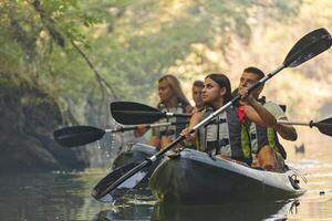 A group of friends enjoying having fun and kayaking while exploring the calm river, surrounding forest and large natural river canyons photo
