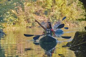 A group of friends enjoying having fun and kayaking while exploring the calm river, surrounding forest and large natural river canyons photo