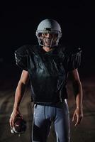 American Football Field. Lonely Athlete Warrior Standing on a Field Holds his Helmet and Ready to Play. Player Preparing to Run, Attack and Score Touchdown. photo