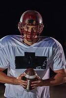 American Football Field. Lonely Athlete Warrior Standing on a Field Holds his Helmet and Ready to Play. Player Preparing to Run, Attack and Score Touchdown. photo