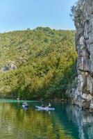 A group of friends enjoying having fun and kayaking while exploring the calm river, surrounding forest and large natural river canyons photo