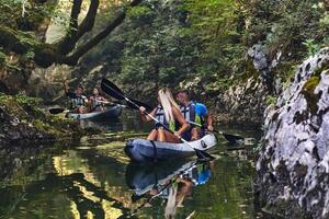 A group of friends enjoying having fun and kayaking while exploring the calm river, surrounding forest and large natural river canyons photo