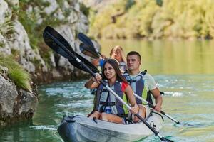 A group of friends enjoying having fun and kayaking while exploring the calm river, surrounding forest and large natural river canyons photo