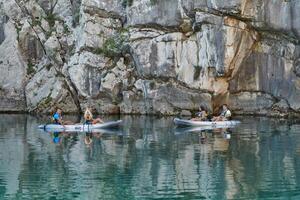 A group of friends enjoying having fun and kayaking while exploring the calm river, surrounding forest and large natural river canyons photo
