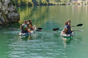 A group of friends enjoying having fun and kayaking while exploring the calm river, surrounding forest and large natural river canyons photo