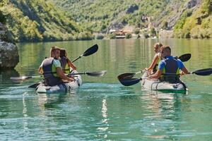 A group of friends enjoying having fun and kayaking while exploring the calm river, surrounding forest and large natural river canyons photo