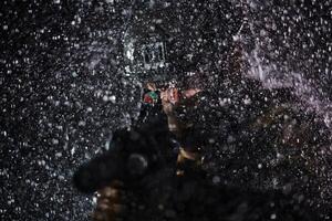 Army soldier in Combat Uniforms with an assault rifle, plate carrier and combat helmet going on a dangerous mission on a rainy night. photo