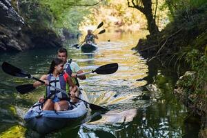 A group of friends enjoying having fun and kayaking while exploring the calm river, surrounding forest and large natural river canyons photo