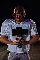 American Football Field. Lonely Athlete Warrior Standing on a Field Holds his Helmet and Ready to Play. Player Preparing to Run, Attack and Score Touchdown. photo