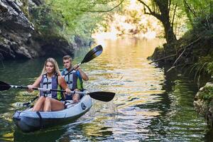 A group of friends enjoying having fun and kayaking while exploring the calm river, surrounding forest and large natural river canyons photo