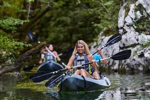 A group of friends enjoying having fun and kayaking while exploring the calm river, surrounding forest and large natural river canyons photo