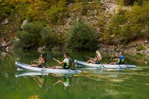 A group of friends enjoying having fun and kayaking while exploring the calm river, surrounding forest and large natural river canyons photo