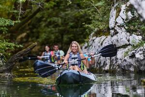 A group of friends enjoying having fun and kayaking while exploring the calm river, surrounding forest and large natural river canyons photo