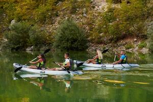 A group of friends enjoying having fun and kayaking while exploring the calm river, surrounding forest and large natural river canyons photo