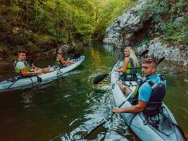 A group of friends enjoying having fun and kayaking while exploring the calm river, surrounding forest and large natural river canyons photo