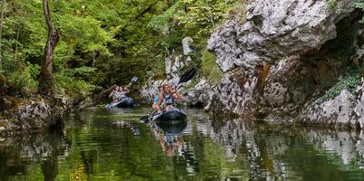A group of friends enjoying having fun and kayaking while exploring the calm river, surrounding forest and large natural river canyons photo