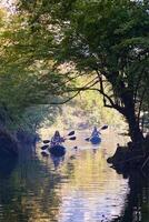 A group of friends enjoying having fun and kayaking while exploring the calm river, surrounding forest and large natural river canyons photo