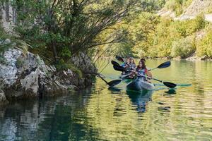 A group of friends enjoying having fun and kayaking while exploring the calm river, surrounding forest and large natural river canyons photo