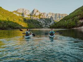 A group of friends enjoying having fun and kayaking while exploring the calm river, surrounding forest and large natural river canyons photo