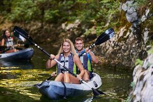 A group of friends enjoying having fun and kayaking while exploring the calm river, surrounding forest and large natural river canyons photo