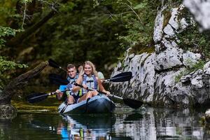 A group of friends enjoying having fun and kayaking while exploring the calm river, surrounding forest and large natural river canyons photo