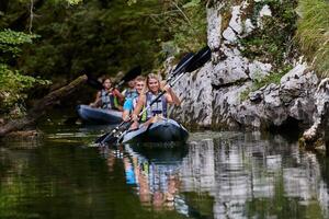 A group of friends enjoying having fun and kayaking while exploring the calm river, surrounding forest and large natural river canyons photo