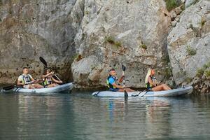 A group of friends enjoying having fun and kayaking while exploring the calm river, surrounding forest and large natural river canyons photo