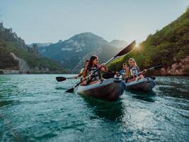 A group of friends enjoying fun and kayaking exploring the calm river, surrounding forest and large natural river canyons during an idyllic sunset. photo
