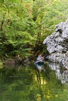 A group of friends enjoying having fun and kayaking while exploring the calm river, surrounding forest and large natural river canyons photo