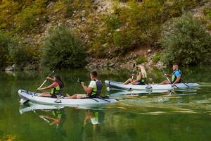 A group of friends enjoying having fun and kayaking while exploring the calm river, surrounding forest and large natural river canyons photo