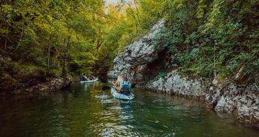 A group of friends enjoying having fun and kayaking while exploring the calm river, surrounding forest and large natural river canyons photo