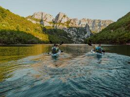 A group of friends enjoying having fun and kayaking while exploring the calm river, surrounding forest and large natural river canyons photo