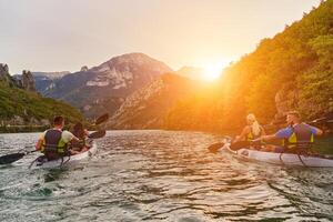 A group of friends enjoying fun and kayaking exploring the calm river, surrounding forest and large natural river canyons during an idyllic sunset. photo
