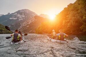 A group of friends enjoying fun and kayaking exploring the calm river, surrounding forest and large natural river canyons during an idyllic sunset. photo