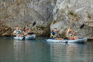 A group of friends enjoying having fun and kayaking while exploring the calm river, surrounding forest and large natural river canyons photo
