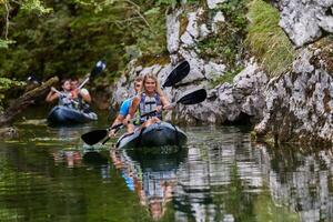 A group of friends enjoying having fun and kayaking while exploring the calm river, surrounding forest and large natural river canyons photo