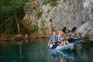 A group of friends enjoying having fun and kayaking while exploring the calm river, surrounding forest and large natural river canyons photo