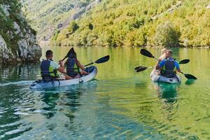A group of friends enjoying having fun and kayaking while exploring the calm river, surrounding forest and large natural river canyons photo