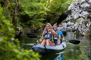 A group of friends enjoying having fun and kayaking while exploring the calm river, surrounding forest and large natural river canyons photo