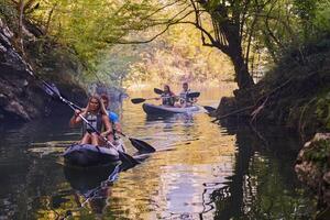 A group of friends enjoying having fun and kayaking while exploring the calm river, surrounding forest and large natural river canyons photo