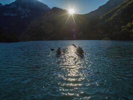 A group of friends enjoying fun and kayaking exploring the calm river, surrounding forest and large natural river canyons during an idyllic sunset. photo