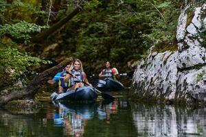 A group of friends enjoying having fun and kayaking while exploring the calm river, surrounding forest and large natural river canyons photo