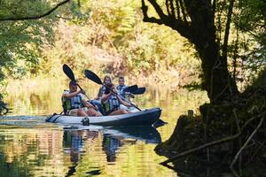 A group of friends enjoying having fun and kayaking while exploring the calm river, surrounding forest and large natural river canyons photo